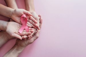 A pink ribbon being held in someone's hands.